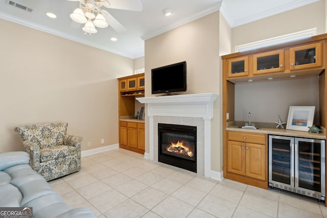 living room featuring wine cooler, light tile patterned flooring, ornamental molding, wet bar, and a fireplace