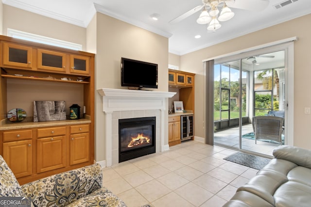 tiled living room with wine cooler, ceiling fan, ornamental molding, and a tile fireplace