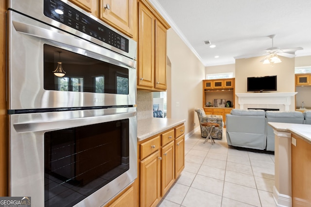 kitchen featuring crown molding, stainless steel double oven, a tile fireplace, and light tile patterned floors