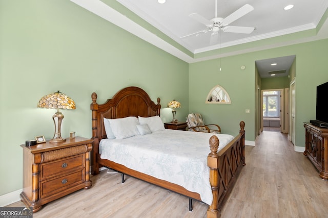 bedroom featuring crown molding, ceiling fan, a raised ceiling, and light wood-type flooring