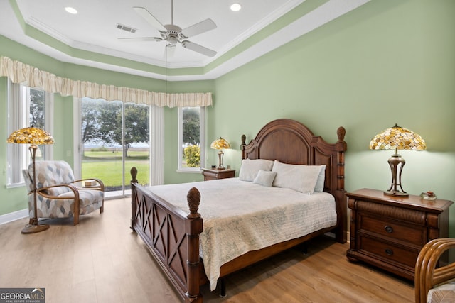 bedroom featuring access to outside, ceiling fan, a tray ceiling, crown molding, and light wood-type flooring