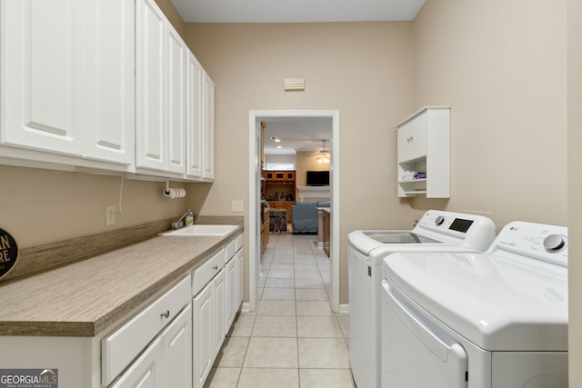 laundry room featuring sink, light tile patterned floors, ceiling fan, cabinets, and separate washer and dryer