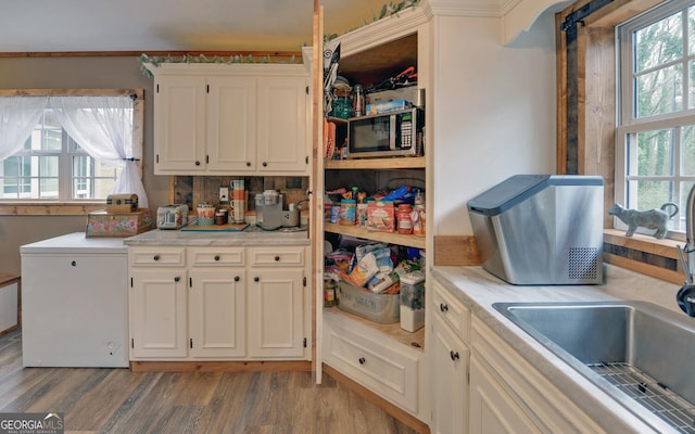 kitchen with white cabinetry, light hardwood / wood-style floors, sink, and a wealth of natural light