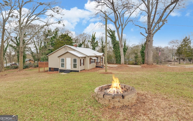 view of front of property with a wooden deck, a front yard, and an outdoor fire pit