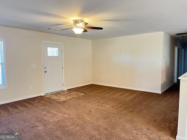 entrance foyer featuring ceiling fan and dark colored carpet