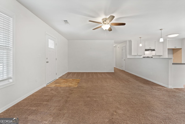 unfurnished living room with carpet, a wealth of natural light, and ceiling fan