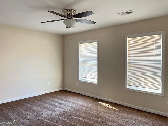 empty room featuring dark colored carpet and ceiling fan