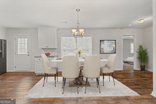 dining space featuring dark wood-type flooring and an inviting chandelier