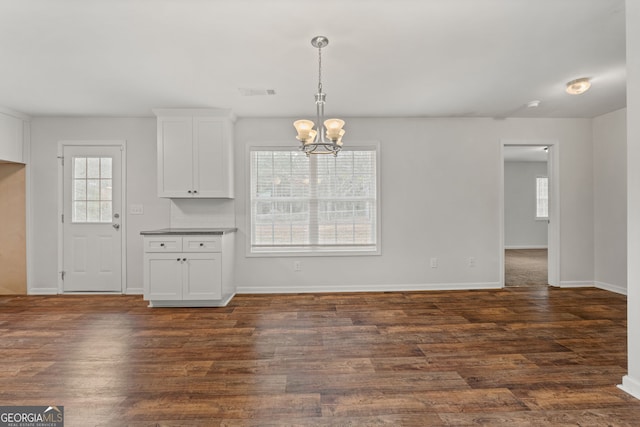 unfurnished dining area featuring dark wood-type flooring and a notable chandelier