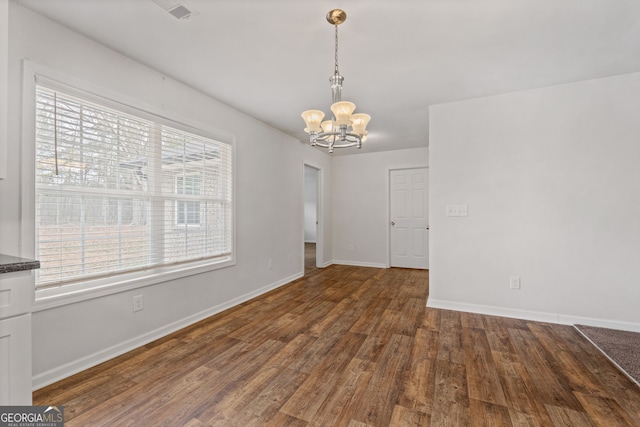 unfurnished dining area with dark wood-type flooring and a notable chandelier