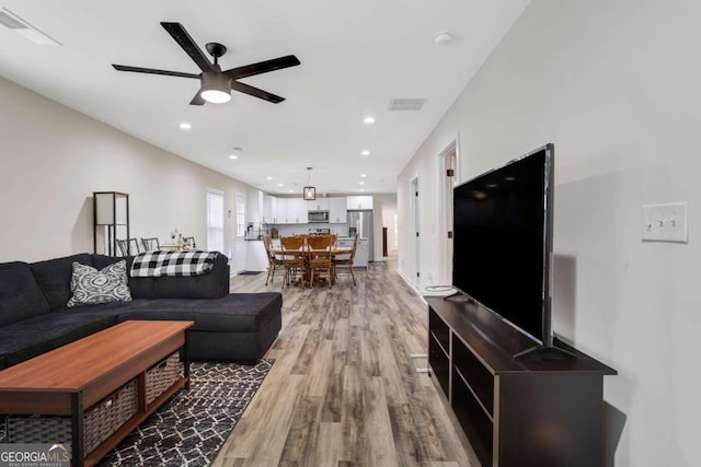 living room featuring wood-type flooring and ceiling fan