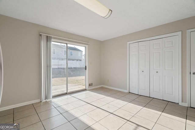 unfurnished bedroom featuring access to outside, light tile patterned floors, and a closet