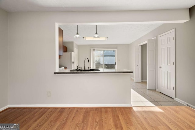 kitchen with hanging light fixtures, sink, kitchen peninsula, and white fridge