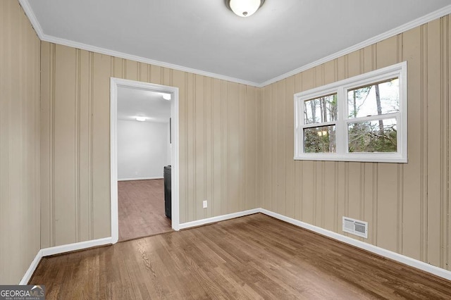 spare room with wood-type flooring and ornamental molding