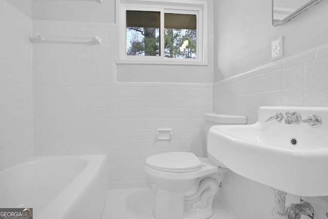 bathroom featuring sink, tile walls, a bathtub, and toilet