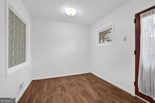 spare room with plenty of natural light and dark hardwood / wood-style floors