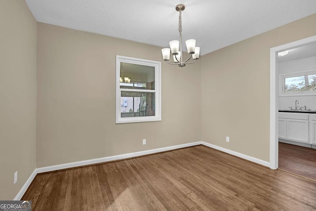 unfurnished room featuring an inviting chandelier, sink, and hardwood / wood-style flooring