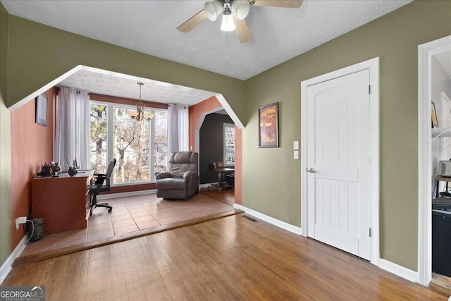 office space with ceiling fan with notable chandelier and light hardwood / wood-style floors