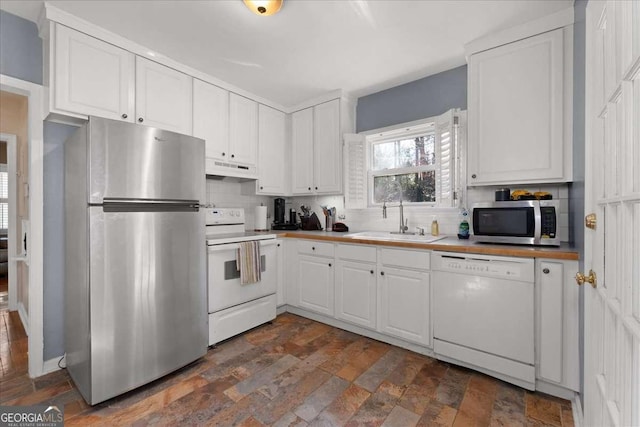 kitchen with tasteful backsplash, appliances with stainless steel finishes, sink, and white cabinets