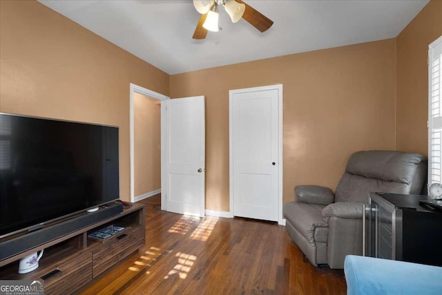 living area with dark wood-type flooring and ceiling fan