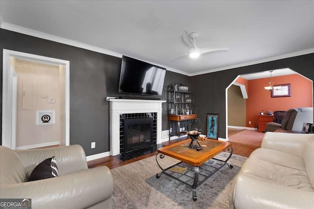 living room with crown molding, hardwood / wood-style flooring, a tile fireplace, and ceiling fan