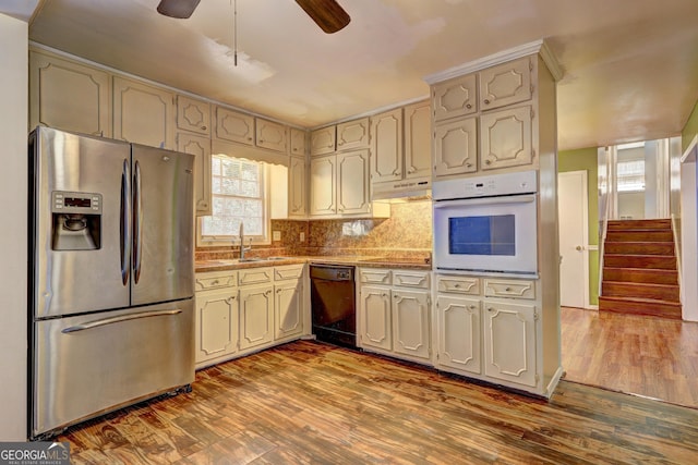 kitchen featuring sink, black appliances, dark hardwood / wood-style floors, cream cabinetry, and backsplash