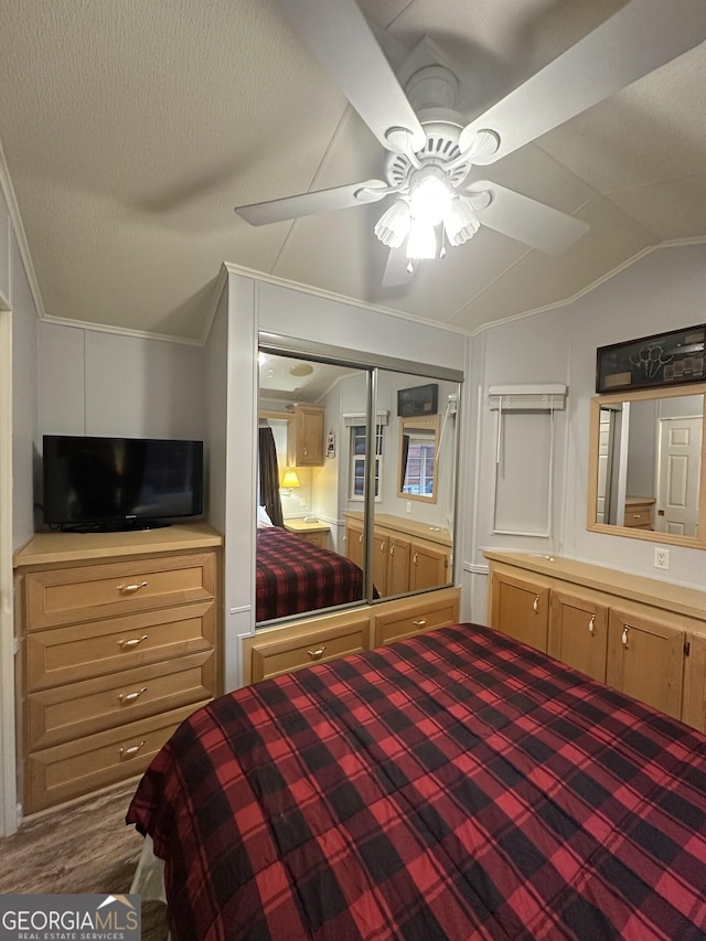 unfurnished bedroom with hardwood / wood-style flooring, ceiling fan, ornamental molding, vaulted ceiling, and a closet