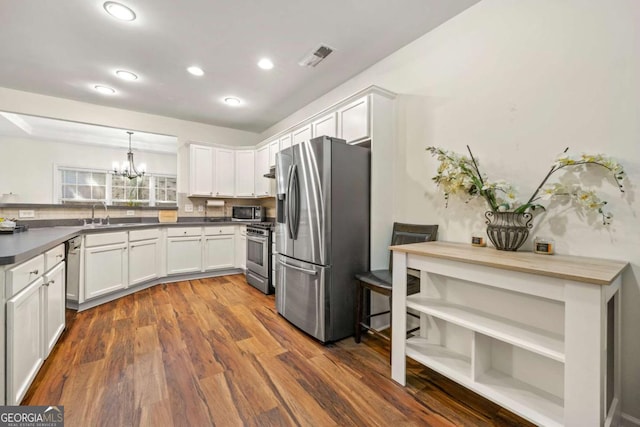 kitchen with sink, appliances with stainless steel finishes, dark hardwood / wood-style flooring, pendant lighting, and white cabinets