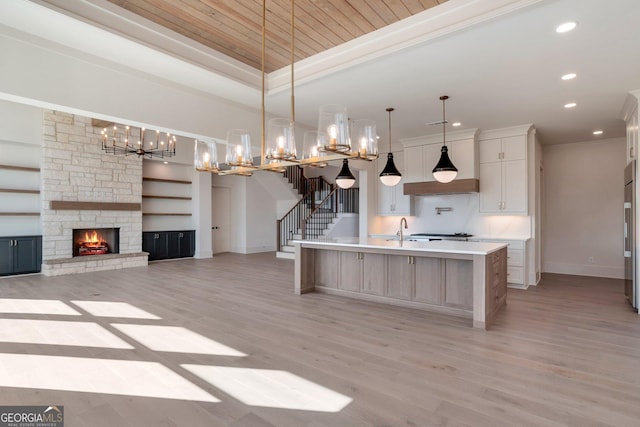 kitchen with pendant lighting, light wood-type flooring, and a large island with sink