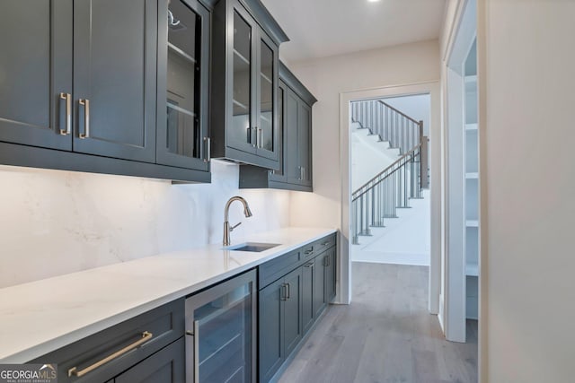 kitchen featuring decorative backsplash, beverage cooler, sink, and light hardwood / wood-style flooring