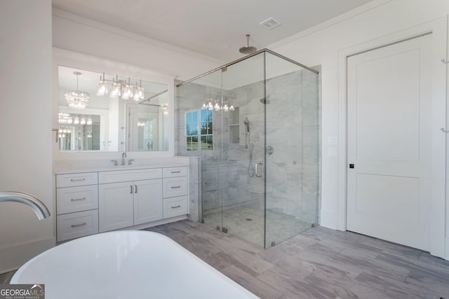 bathroom featuring crown molding, vanity, a shower with shower door, and a notable chandelier