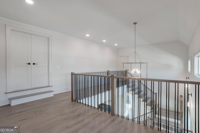 hall featuring lofted ceiling, a notable chandelier, and hardwood / wood-style flooring