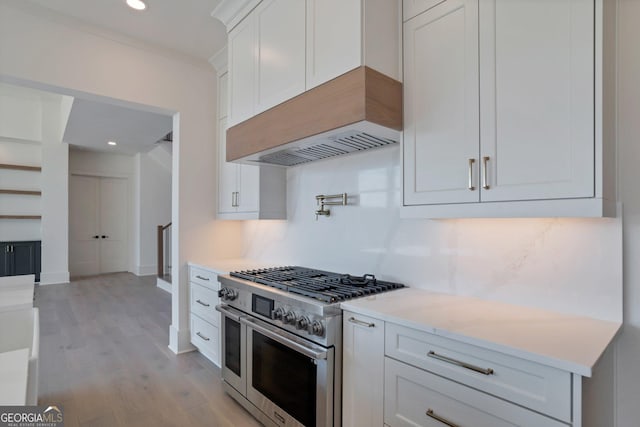 kitchen featuring white cabinetry, decorative backsplash, range with two ovens, ornamental molding, and light hardwood / wood-style floors