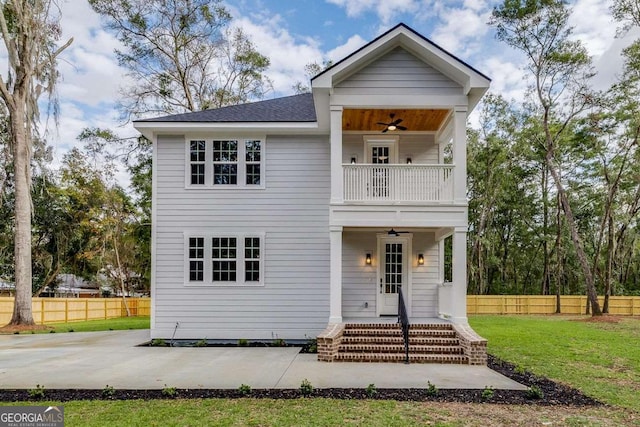 view of front of home with a balcony, ceiling fan, and a front lawn