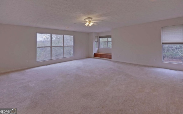 spare room with ceiling fan, light carpet, and a textured ceiling