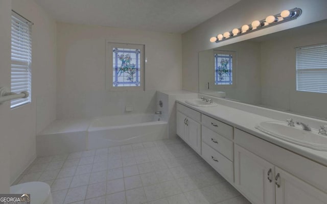 bathroom featuring tile patterned flooring, vanity, a healthy amount of sunlight, and a bathtub