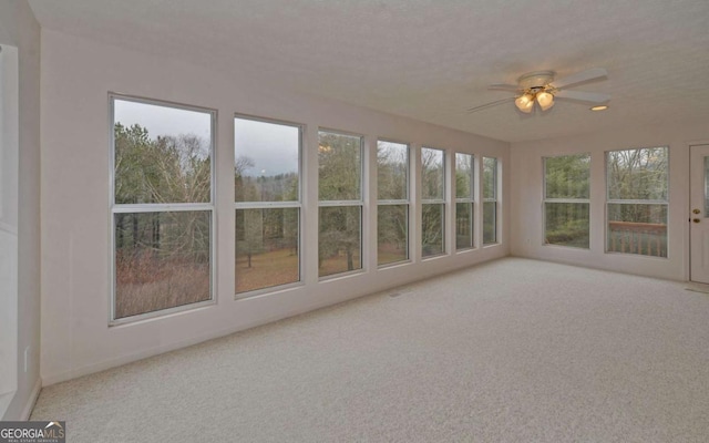 unfurnished sunroom with ceiling fan and a healthy amount of sunlight