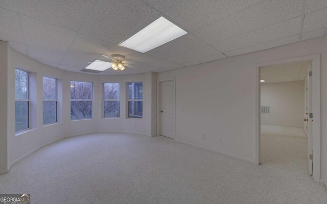 carpeted empty room with ceiling fan and a paneled ceiling