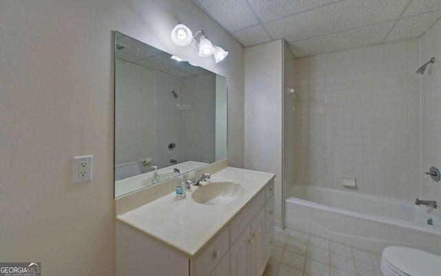 full bathroom featuring tiled shower / bath combo, vanity, toilet, a drop ceiling, and tile patterned floors