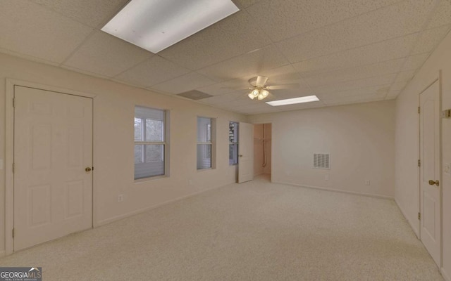 unfurnished room with ceiling fan, a paneled ceiling, and light carpet