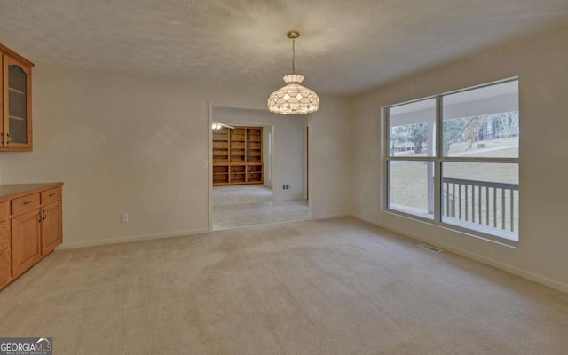 unfurnished dining area featuring light colored carpet and a textured ceiling