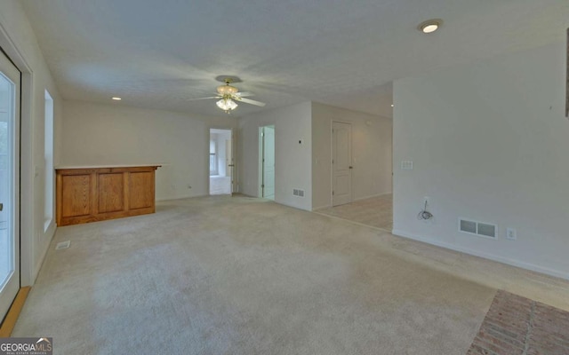 unfurnished living room with light colored carpet and ceiling fan