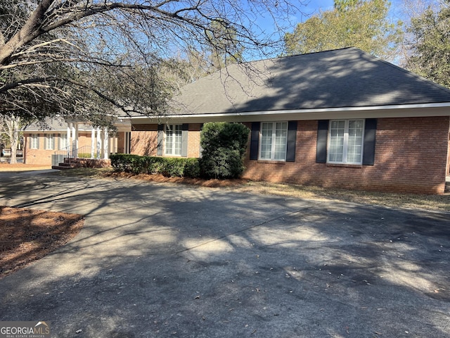 view of front of house featuring a shingled roof and brick siding