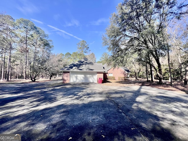 exterior space with driveway, an attached garage, and brick siding