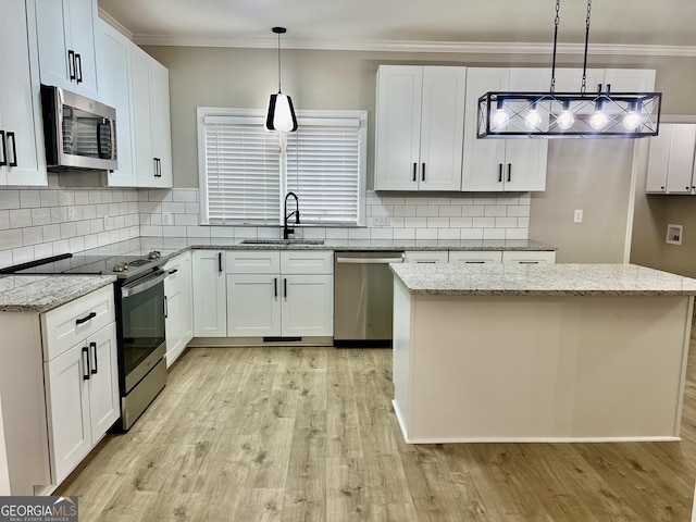 kitchen with hanging light fixtures, appliances with stainless steel finishes, a kitchen island, and white cabinets