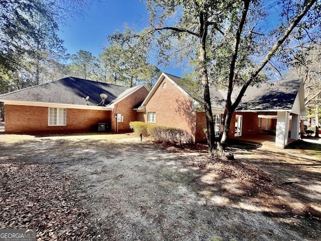 view of side of property featuring gravel driveway and brick siding