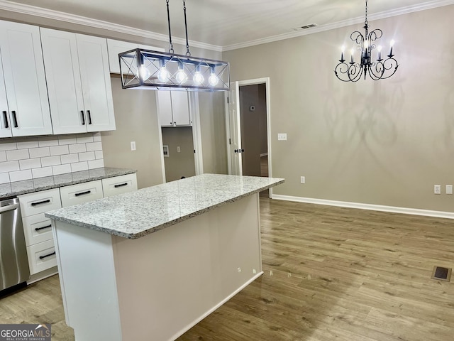 kitchen featuring a center island, light stone counters, white cabinets, and decorative light fixtures