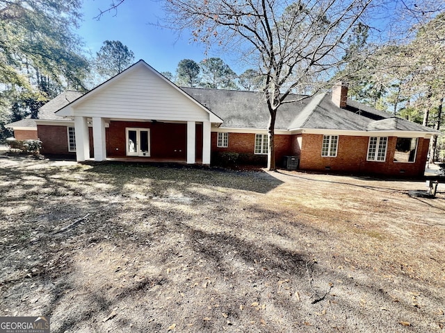 rear view of property with cooling unit, brick siding, driveway, crawl space, and a chimney