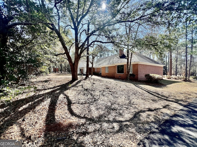 view of side of home featuring brick siding and a chimney