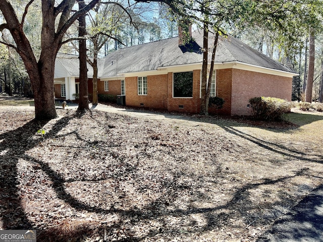 back of house with crawl space, central air condition unit, roof with shingles, and brick siding